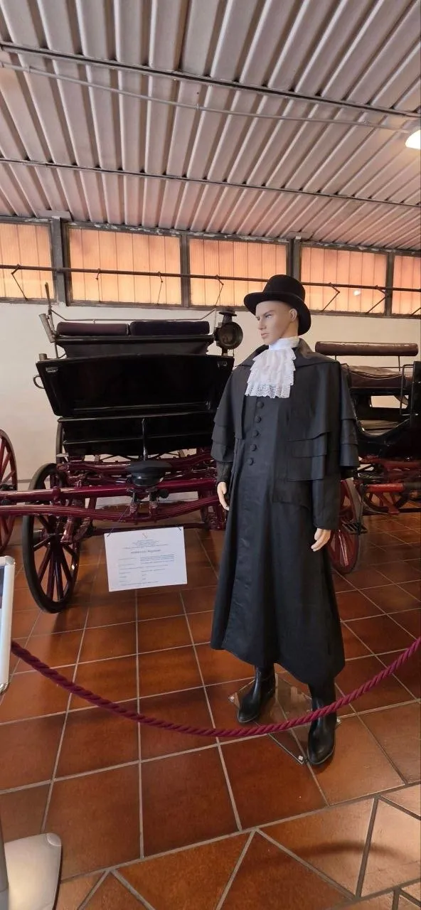Manichino con uniforme storica e cappello nero davanti alle carrozze del museo